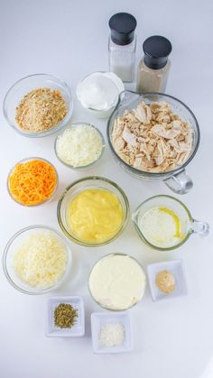 an assortment of ingredients are arranged in bowls on a white counter top, including cheese and chicken