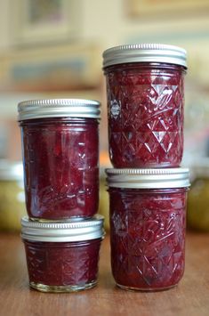 three jars filled with jam sitting on top of a wooden table