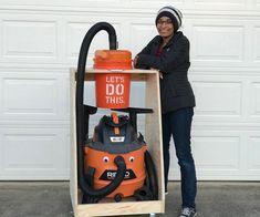 a woman standing next to an orange and black fire extinguisher in front of a garage door