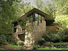 a stone house surrounded by trees in the woods