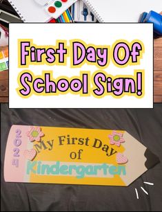 the first day of school sign is shown with supplies on it and in front of them