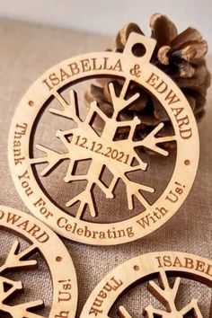 three wooden snowflakes with names on them and pine cones in the background