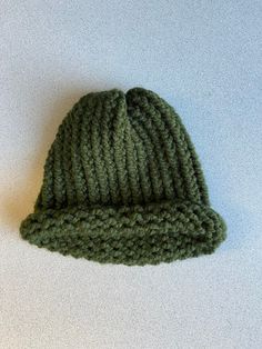 a green knitted hat sitting on top of a white table