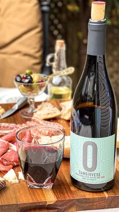 a bottle of wine sitting on top of a wooden table next to a bowl of food