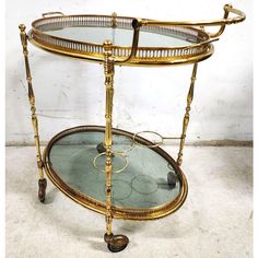 an antique brass serving cart with glass top