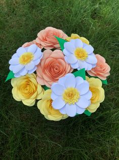 an arrangement of paper flowers in the grass