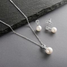 the pearl necklace and earring set is shown on top of a black stone surface