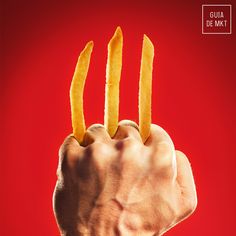 a hand holding two pieces of french fries in front of a red background with mcdonald's logo