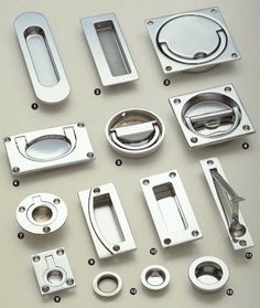 several different types of metal parts on a white surface, including handles and knobs