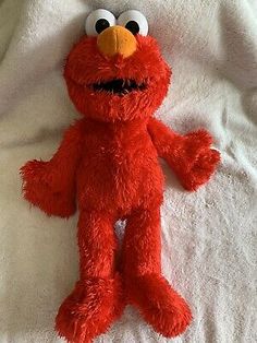 a red stuffed animal is laying on a white sheet