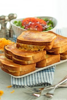 grilled cheese sandwiches on toasted bread with salad in the bowl and fork next to them