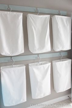 several white towels hanging on hooks in a bathroom