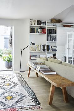 a living room with bookshelves and a rug on the floor in front of it