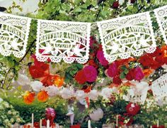 a table topped with lots of cake covered in white frosting next to red and orange flowers