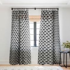 a living room with white walls and black curtains on the window sill, along with a rug