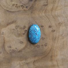 a blue stone sitting on top of a wooden table next to small holes in the wood