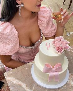 a woman sitting at a table with a cake and wine glass in front of her