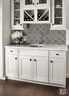 a kitchen with white cabinets and grey tile backsplashing on the wall above the sink