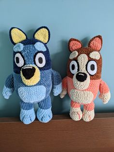 two stuffed animals sitting on top of a wooden shelf next to each other in front of a blue wall