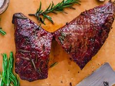 two steaks on a cutting board with herbs