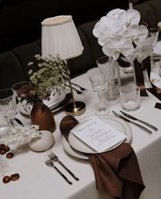 the table is set with white flowers and silverware