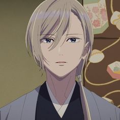 an anime character with blonde hair and blue eyes looking at the camera while standing in front of a wall