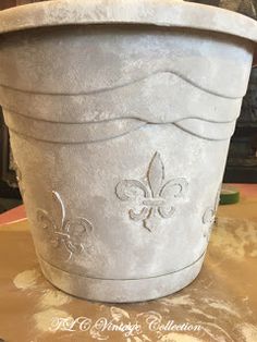 a white pot with a fleur de lis design on it sitting on a table