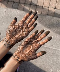 two hands with henna tattoos on them