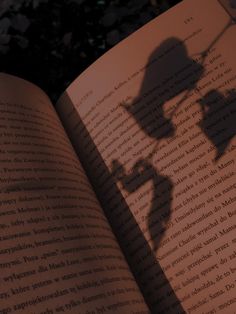 an open book with the shadow of a person casting a shadow on it