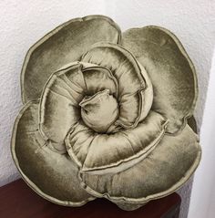 a flower shaped pillow sitting on top of a wooden table next to a white wall