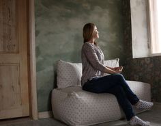 a woman sitting on top of a couch next to a window