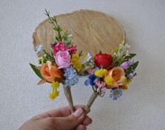 a person holding two flowers in front of a wooden platter on the wall behind them