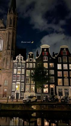 an old building is lit up at night with the moon in the sky above it