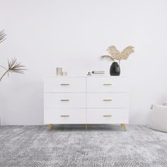 a white dresser sitting next to a potted plant