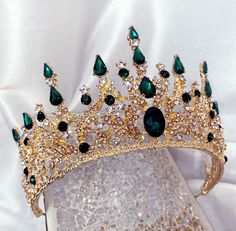 a gold tiara with green and clear stones on it's headpieces