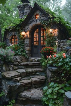 a small stone house surrounded by greenery and flowers with lights on in the windows