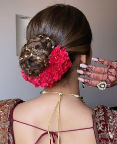 the back of a woman's head with flowers in her hair and jewelry on it