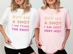 two women wearing t - shirts that say buy me a shot and i am tying the knot