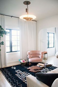 a living room filled with furniture and a large rug on the floor in front of a window