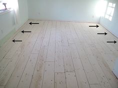 an empty room with white walls and wood flooring in the corner, showing three arrows pointing to the right