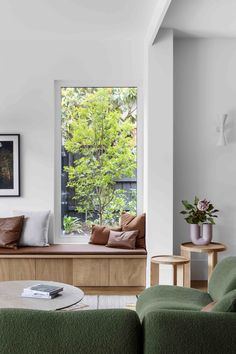 a living room filled with furniture next to a window covered in green pillows and blankets