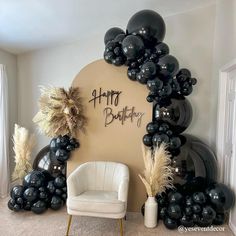 black and white balloons are arranged in the shape of a happy birthday arch, along with a chair