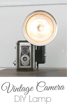 an old fashioned camera sitting on top of a wooden table next to a light bulb