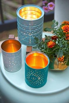 three tea light candles sitting on top of a white table next to some potted plants