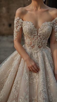 a woman wearing a wedding dress with an off the shoulder neckline and flowers on it