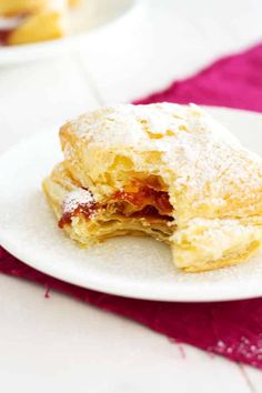 a powdered sugar filled pastry on a white plate next to a pink table cloth