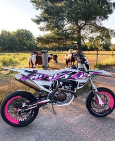 a pink and black motorcycle parked on the side of a road next to some horses