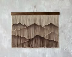 the wall hanging is made out of wood and has long fringes on each side