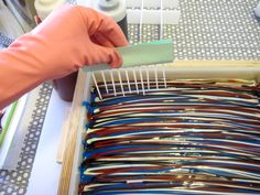 a person is holding a comb over a drawer full of different colored hair dyes