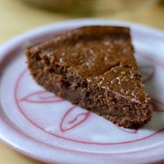 a piece of chocolate cake sitting on top of a white and pink plate with red designs